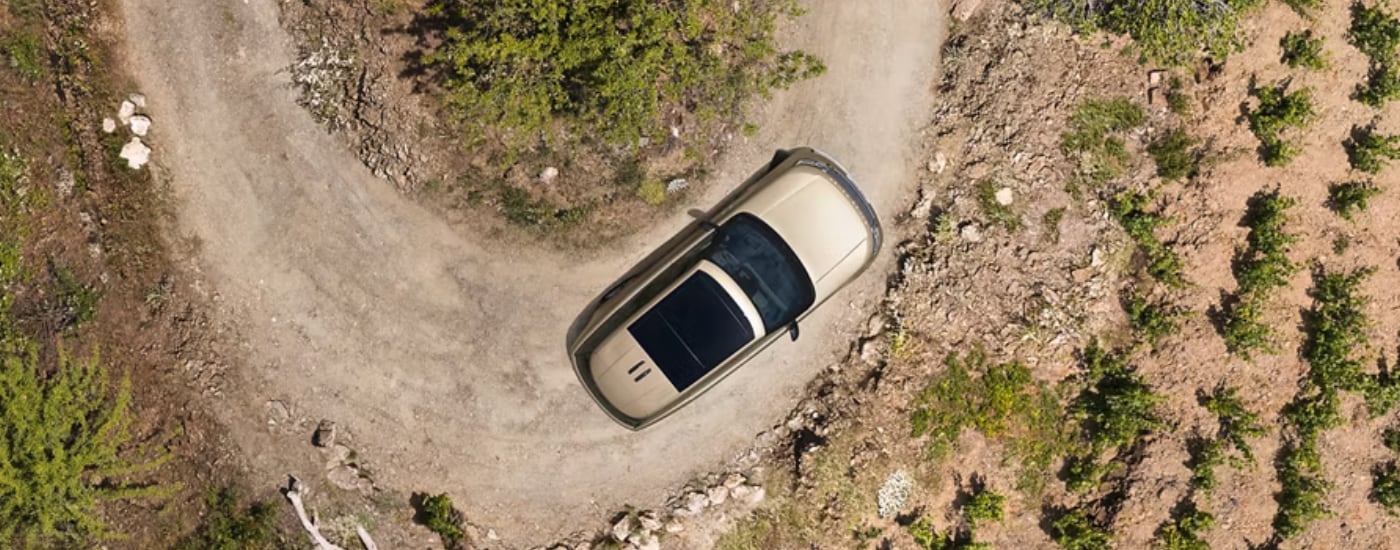 Top view of a tan 2026 Land Rover Range Rover driving on a winding dirt road