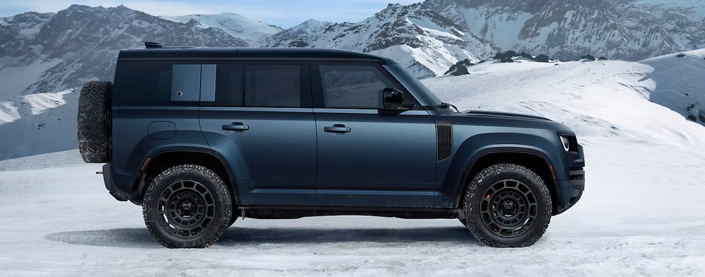 Side of a blue 2026 Land Rover Defender parked on ice.