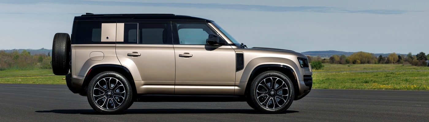 Tan Defender 130 SUV parked on a runway on a sunny day