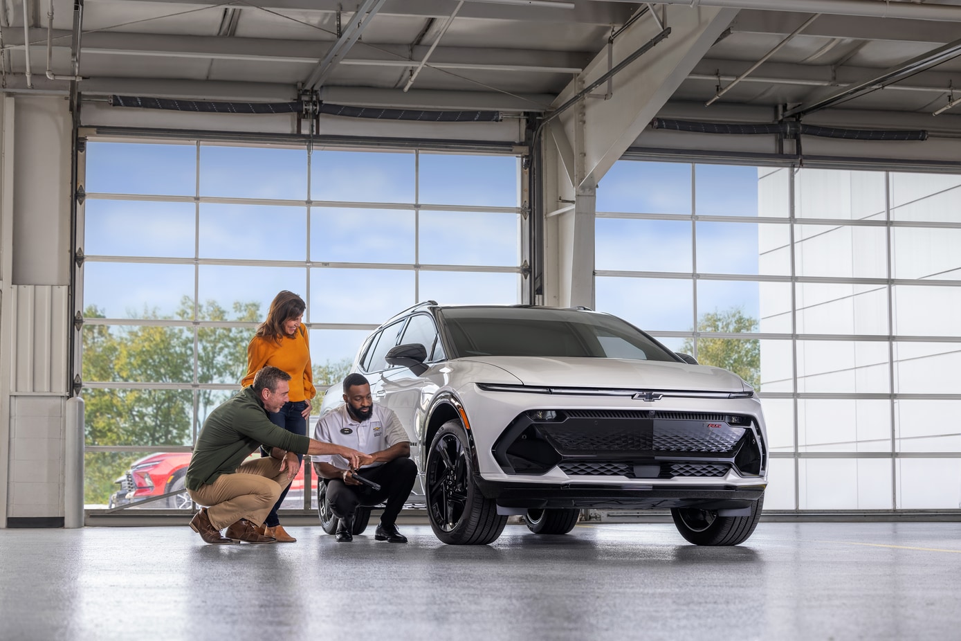  couple excitedly looking at Chevy Equinox EV in service bay with service technician