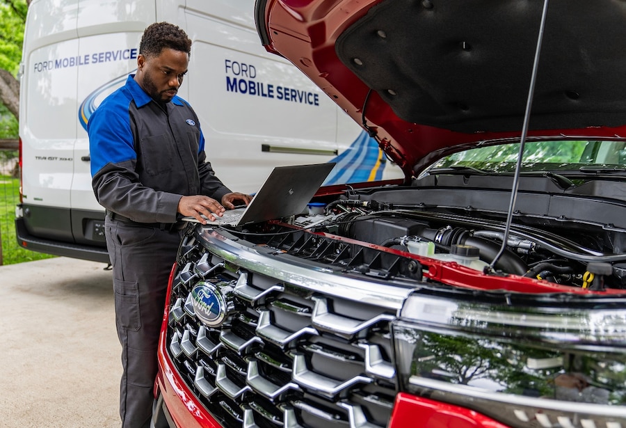 Lasco Ford mobile service technician performing AC service under hood Fenton Michigan
