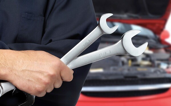 A mechanic holding two wrenches
