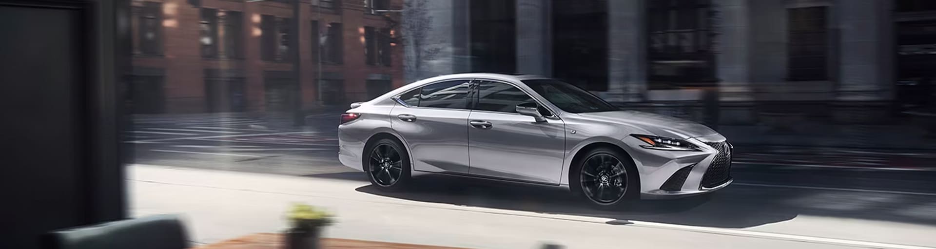 A silver 2025 Lexus ES driving through a city