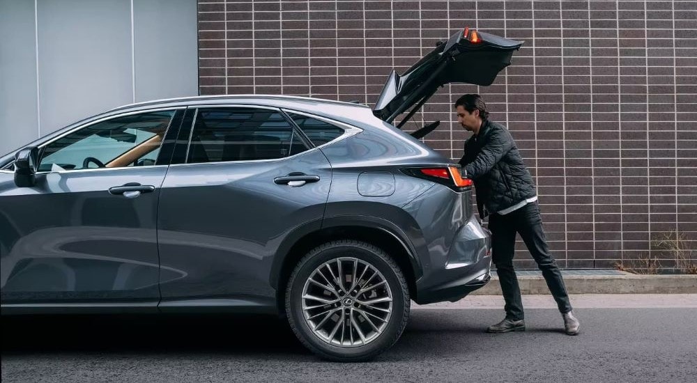 A person is shown opening the liftgate on a blue 2024 Lexus NX.