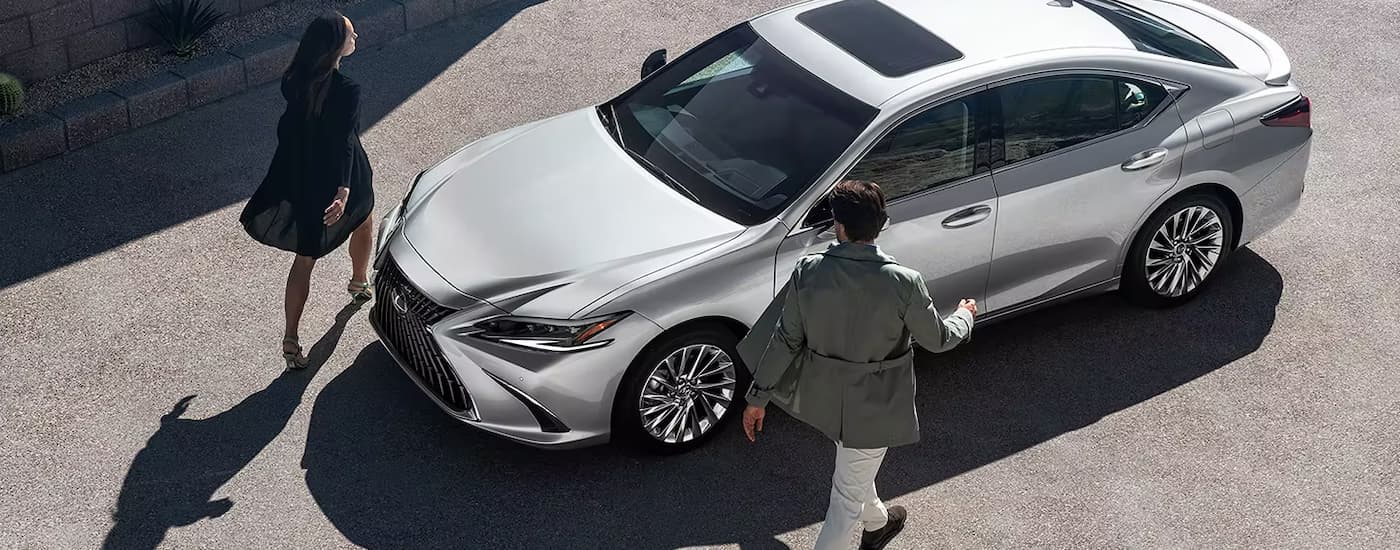 Two people are shown walking towards a 2024 Lexus ES parked on a street.