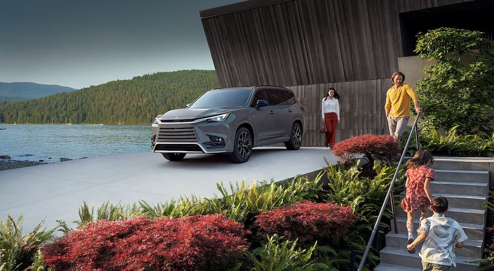 A gray 2024 Lexus TX500h is shown parked near a lake.