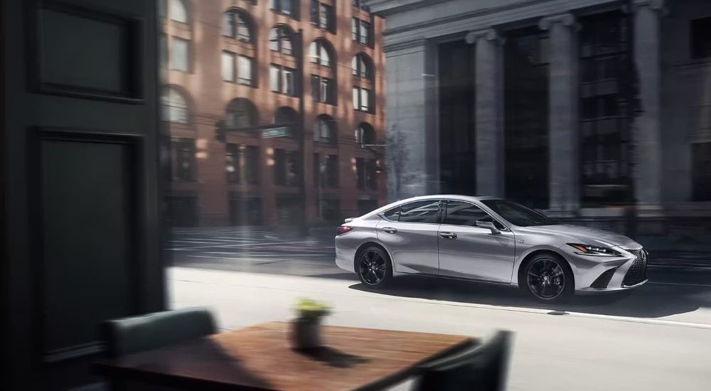 Lexus ES for Sale - 2024 Lexus ES - Side.jpg A silver 2024 Lexus ES for sale is shown driving on a city street.