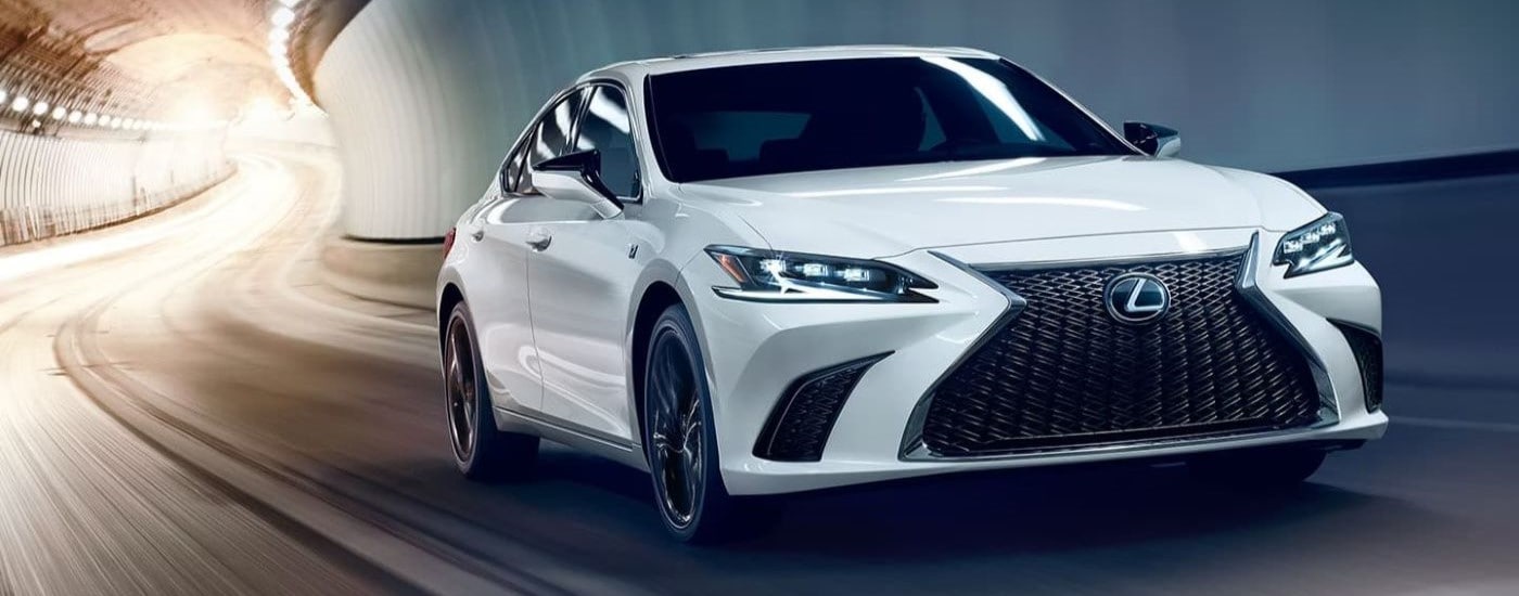 A white 2024 Lexus ES is shown driving though a tunnel after leaving a Lexus dealer near you.