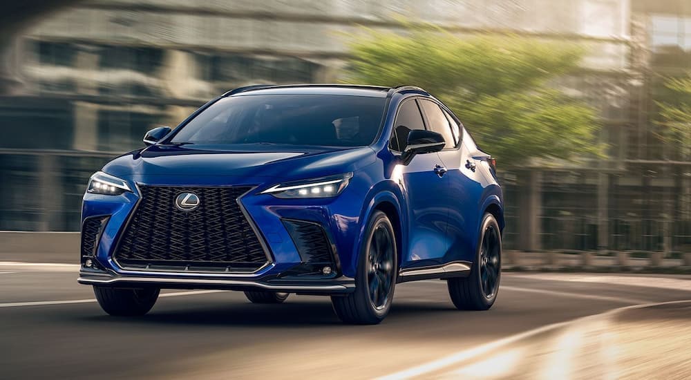 One of many popular Lexus Evs, a blue 2024 NX 450h+, is shown driving on a city street.