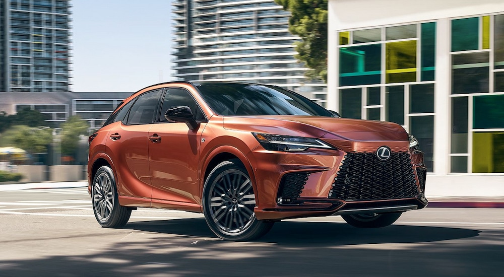 A copper colored 2024 Lexus RX F SPORT driving in the city.