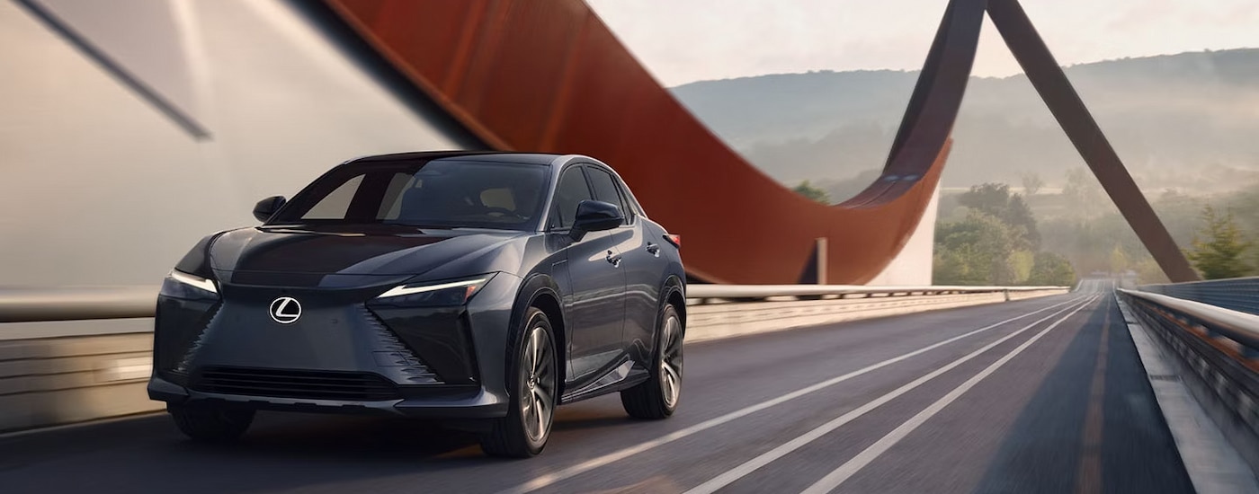 A grey 2024 Lexus RZ driving over a bridge to a Lexus dealer near Great Neck.