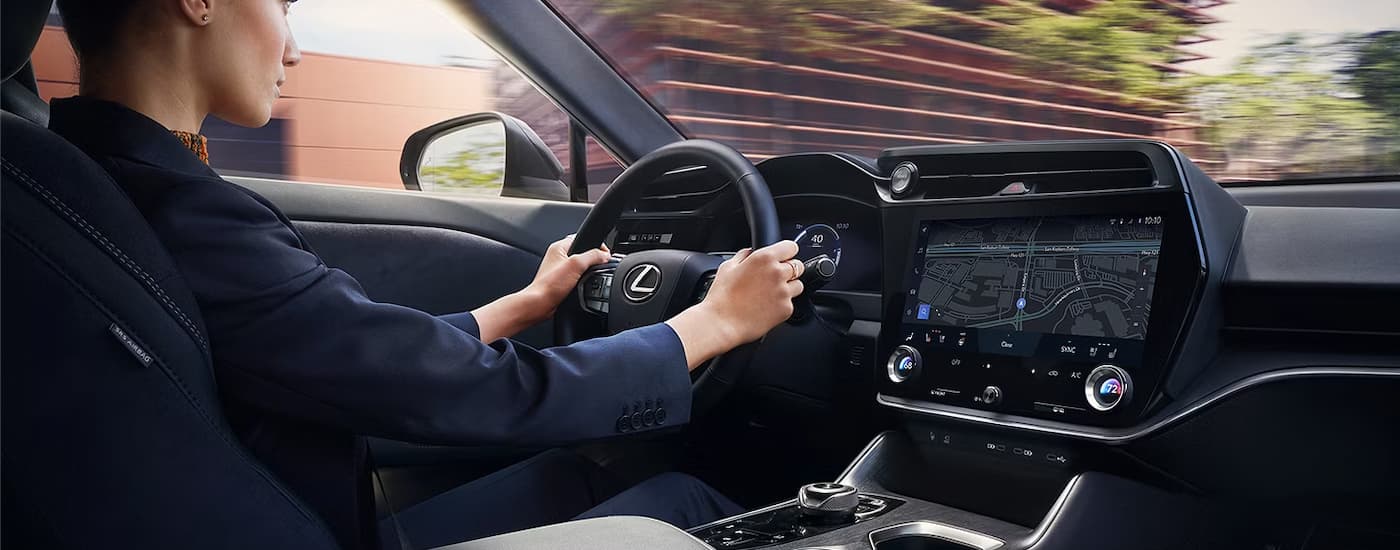 A person is driving in a 2024 Lexus RZ through a city.