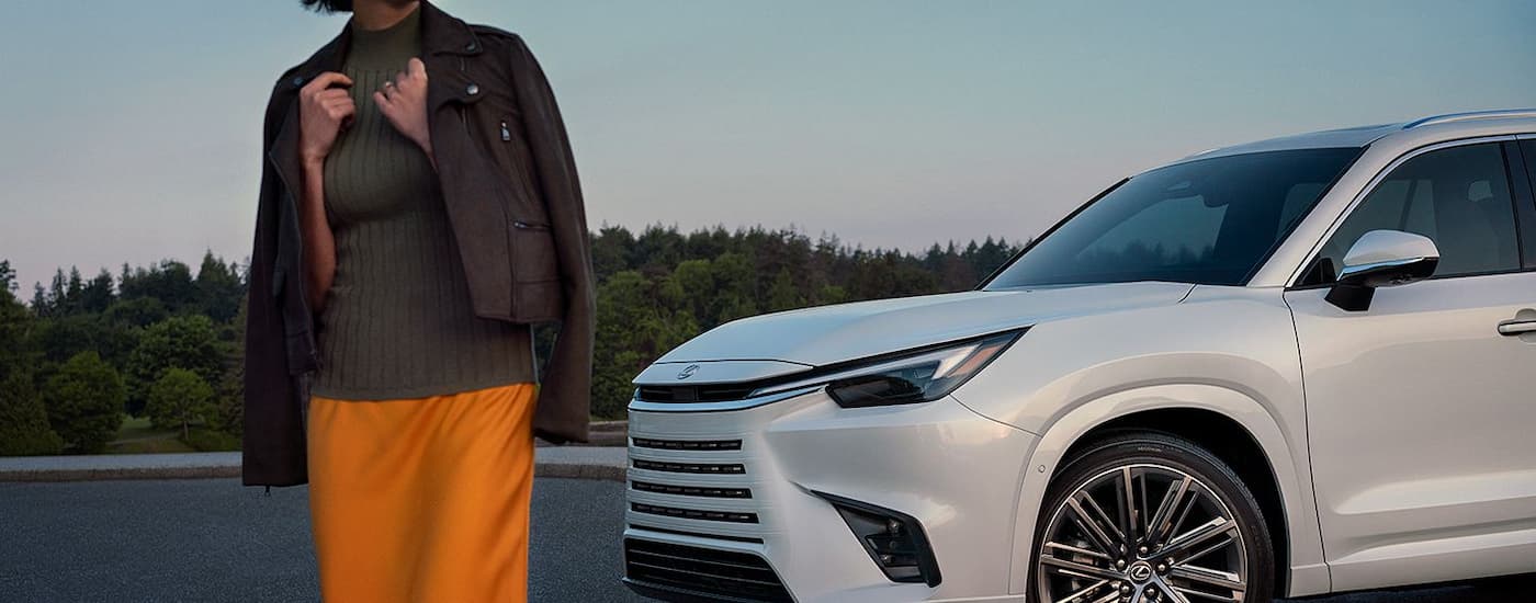 A person is walking away from a parked white 2024 Lexus TX.