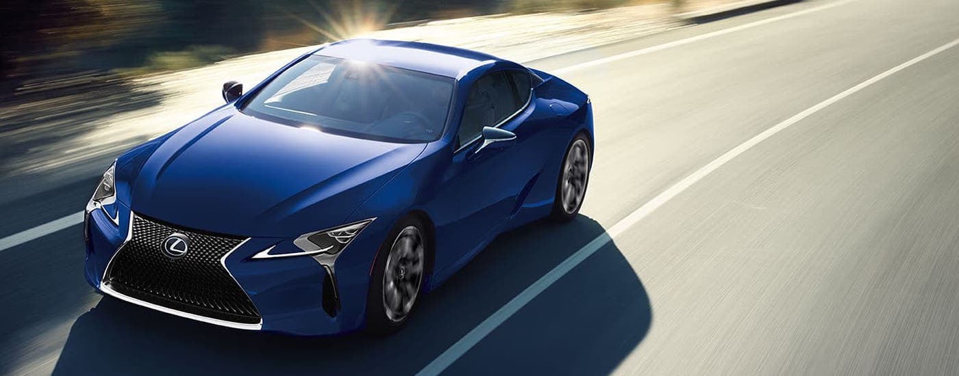 A blue 2024 Lexus LC is driving on a winding road.