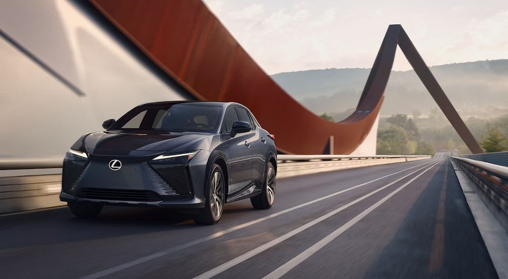 A grey 2024 Lexus RZ driving across a modern bridge.