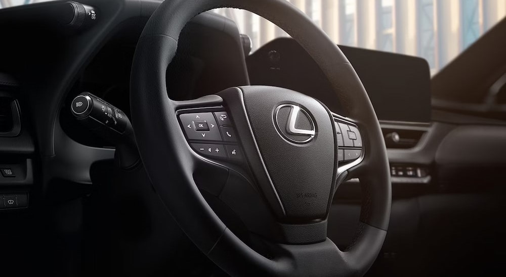 A close-up of the steering wheel and dash in a 2024 Lexus UX 250h is shown.