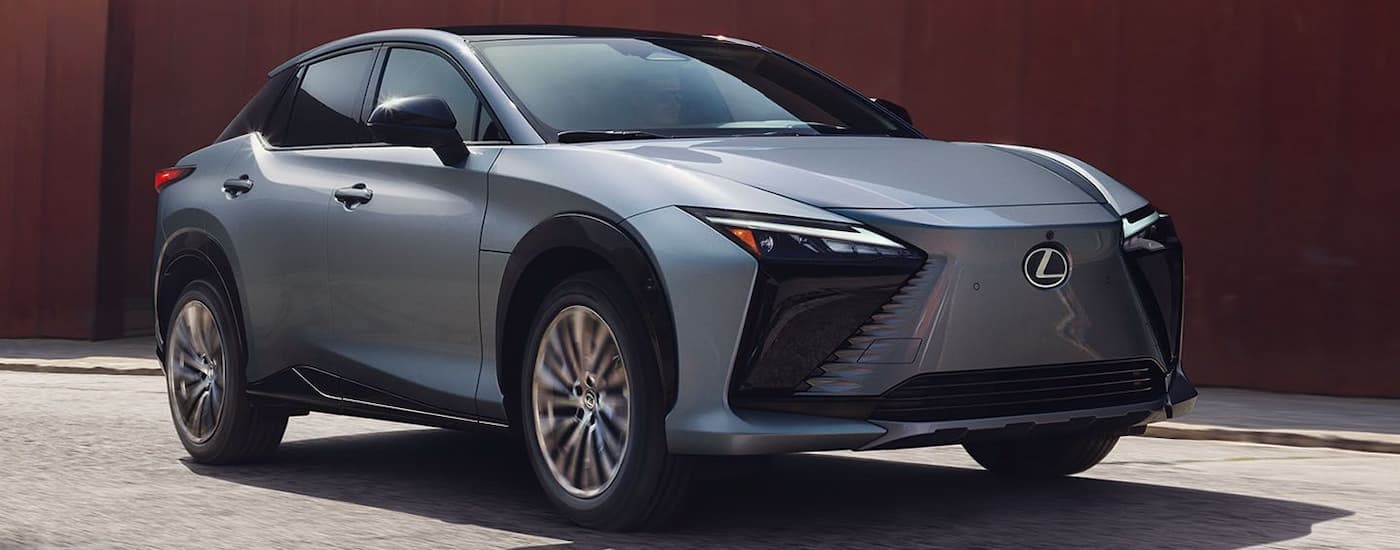 A grey and black 2024 Lexus RZ is parked on a stone driveway.