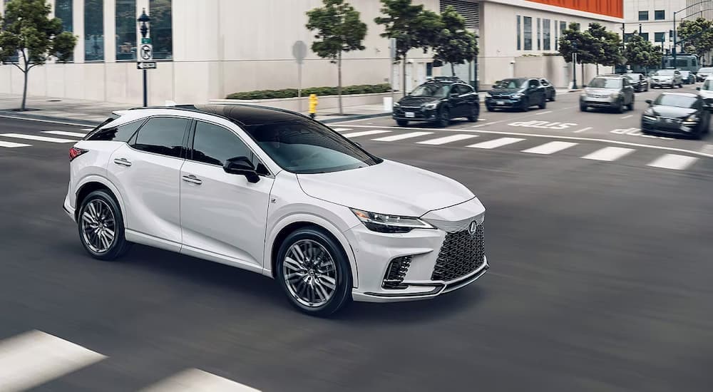 A white 2023 Lexus RS is shown driving on a city street.