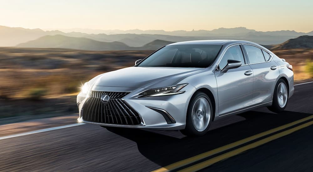 One of many famous Lexus EVs, a silver 2024 Lexus ES Hybrid, is shown driving on a highway.