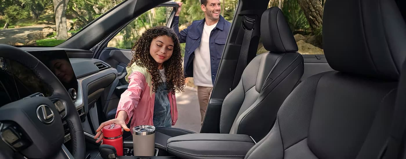 A child is shown taking a water bottle out of the center console cup holder in a 2024 Lexus TX.