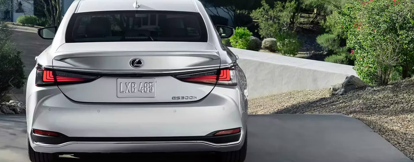 A silver 2023 Lexus ES300h is shown from the rear parked in a driveway.