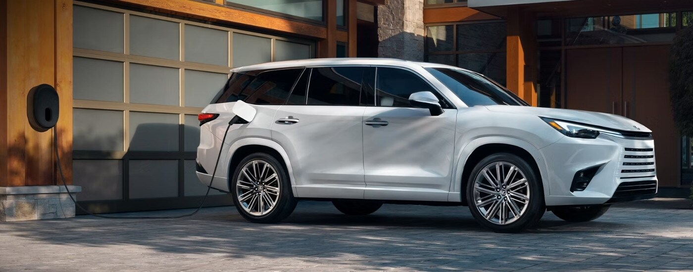 White 2026 Lexus TX PHEV charging in front of a garage