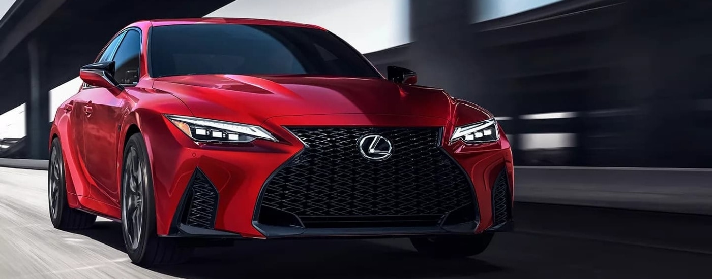Red 2023 used Lexus IS for sale near Bloomington driving near an overpass