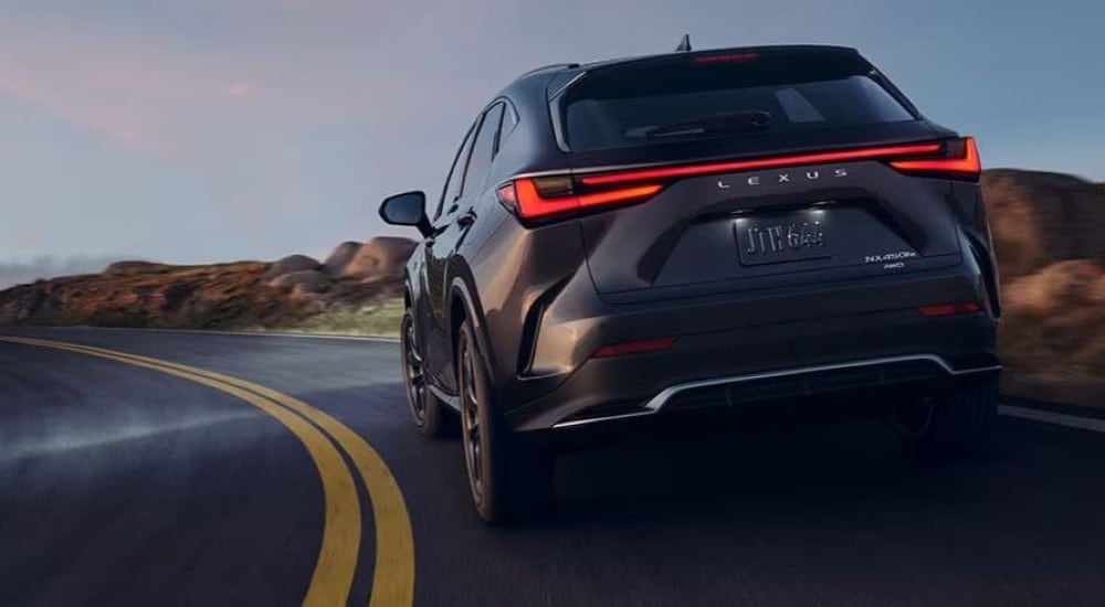A grey 2024 Lexus NX 450h+ is shown rounding a corner after looking at a Lexus NX for sale.