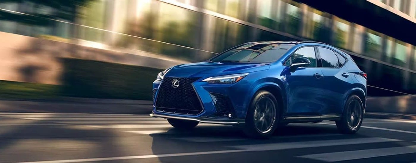 A blue 2024 Lexus NX for sale is shown driving on a city street.