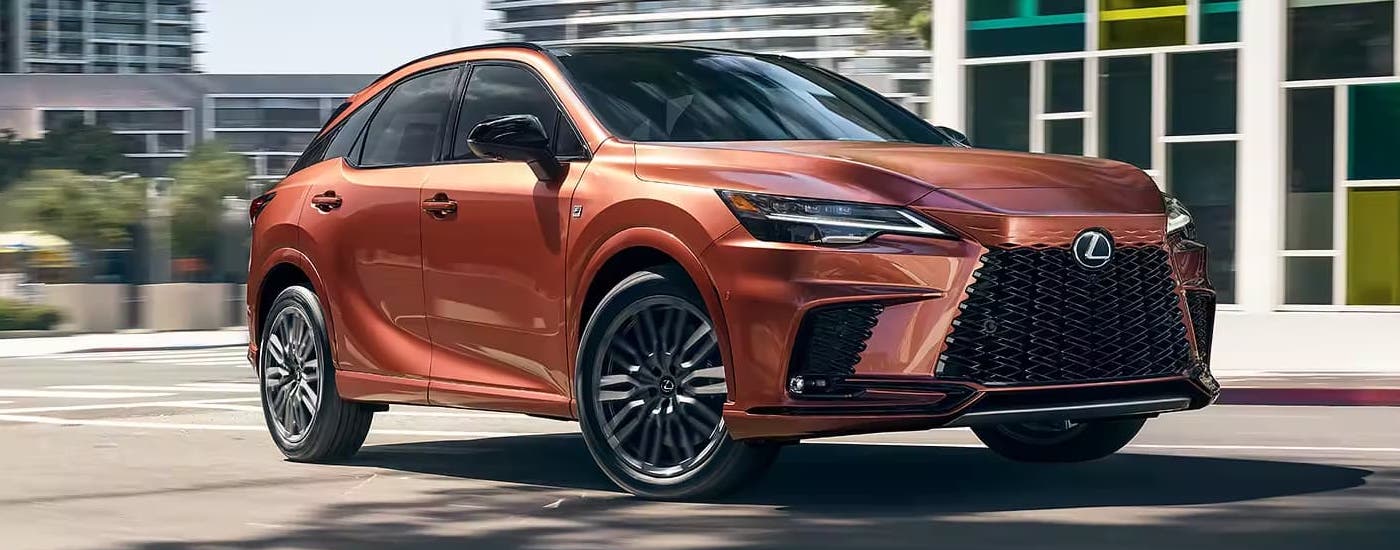 A gold 2023 Lexus RX 350 is shown driving on a city street.
