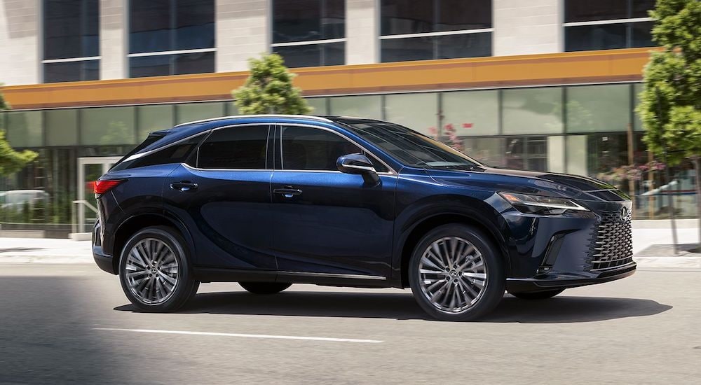 A blue 2024 Lexus RX is shown from the side on a city street after leaving a Lexus dealer near Bayside.