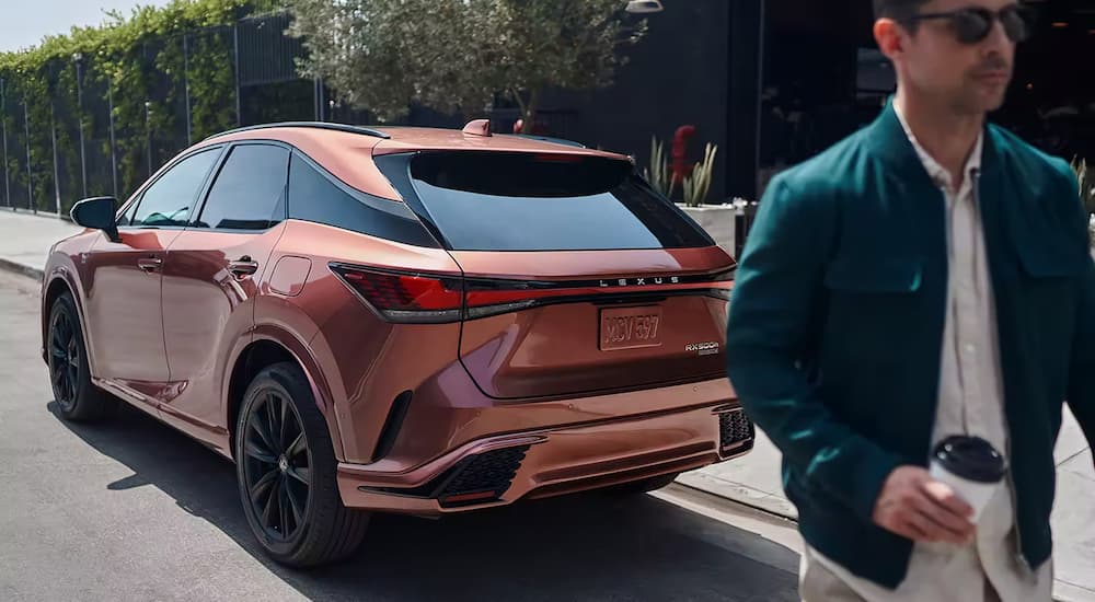 An orange 2023 Lexus RX 350 is shown from the rear parked on the side of a city street.