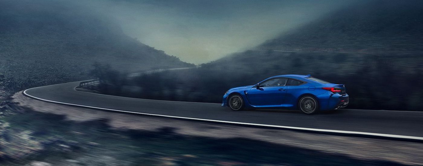 A blue 2023 Lexus RCF is shown from the side on a winding road.