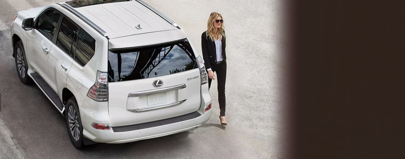 A woman is shown past a 2023 Lexus GX parked on the side of a city street.