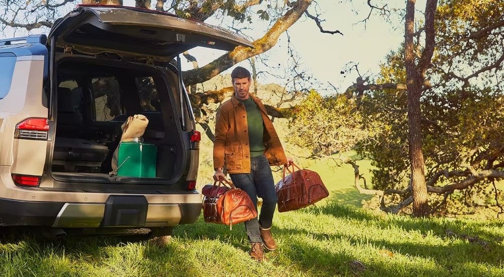 A person is shown stowing luggage in the trunk of a tan 2024 Lexus GX.