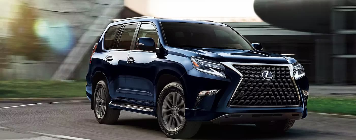 A blue 2023 Lexus GX is shown driving on a winding road. id=