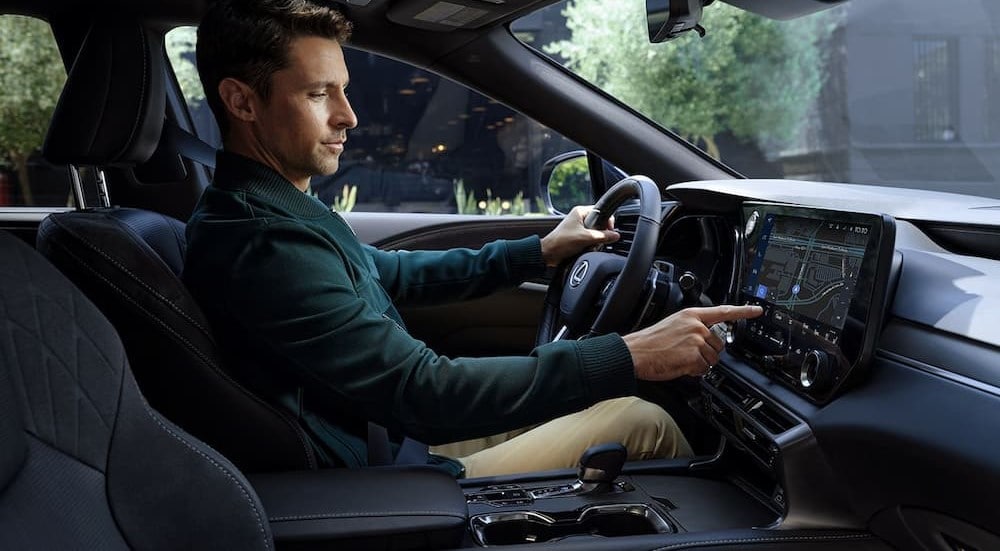 A person is shown touching the infotainment screen in the black interior in a 2024 Lexus RX.