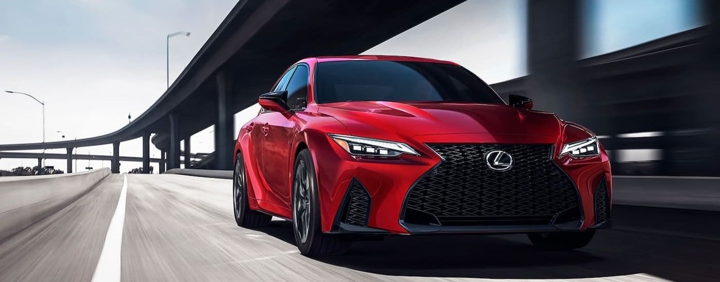 A red 2024 Lexus IS is shown driving near a Lexus dealer near Freeport.