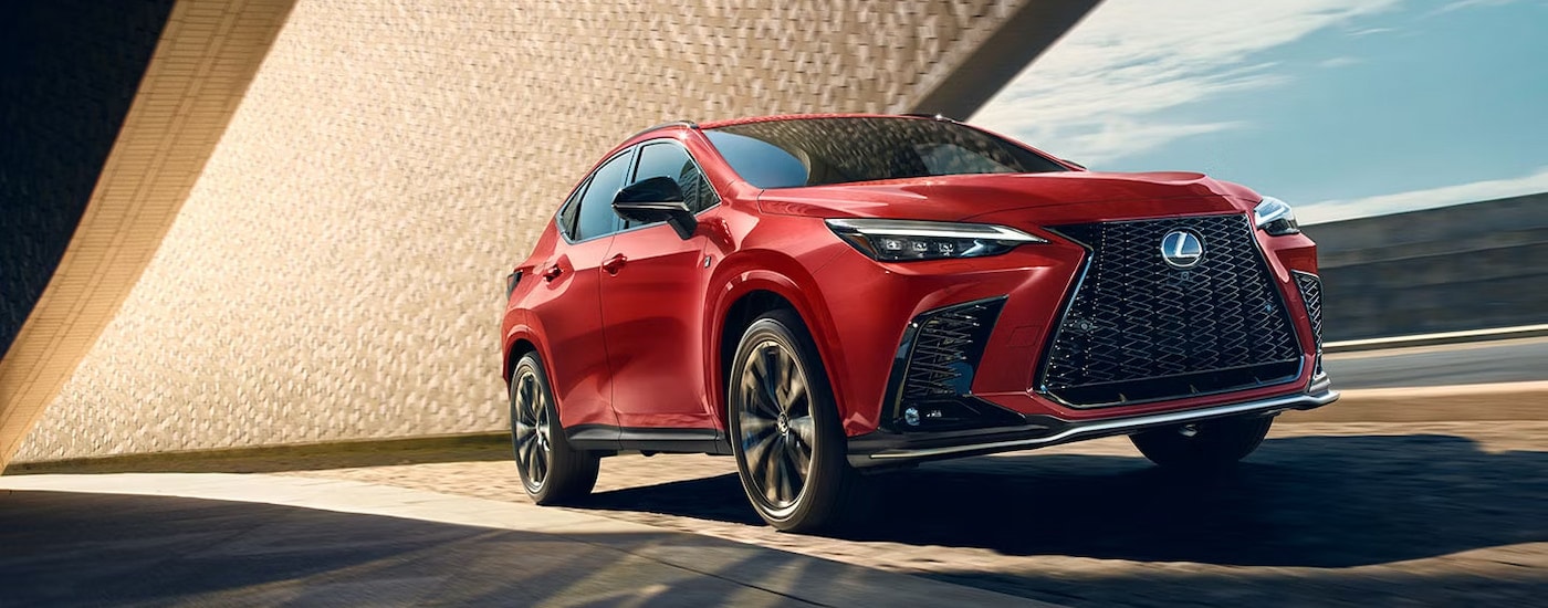 A red 2025 Lexus NX 450h+ driving on a bridge.