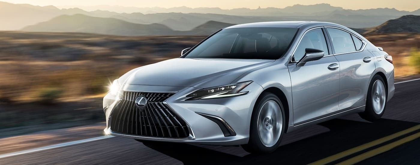 A silver 2024 Lexus ES is shown driving on a highway.