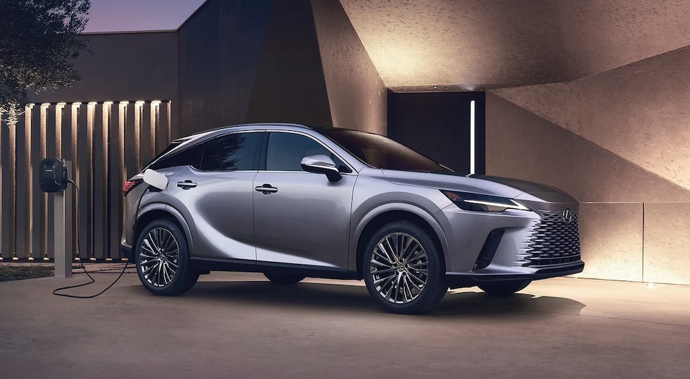 A silver 2024 Lexus RX Plug-In Hybrid charging in a modern driveway.