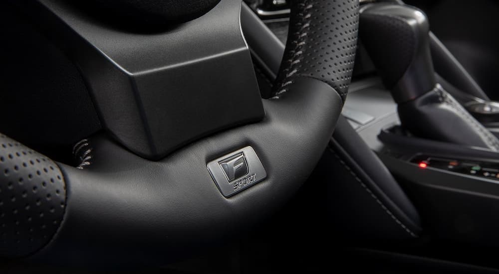 A close up of the black interior and steering wheel of a 2024 Lexus IS.