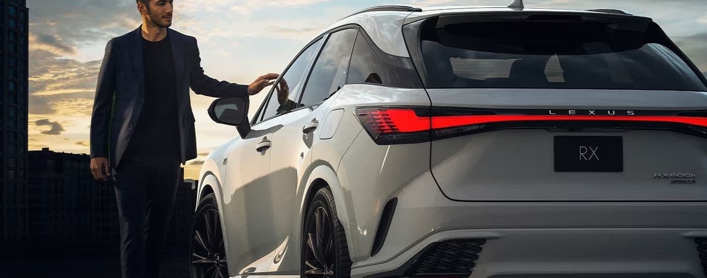 A man is walking by a parked white 2024 Lexus RX.