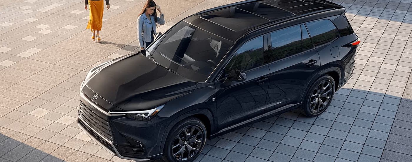 A black 2024 Lexus TX is parked on a stone area.