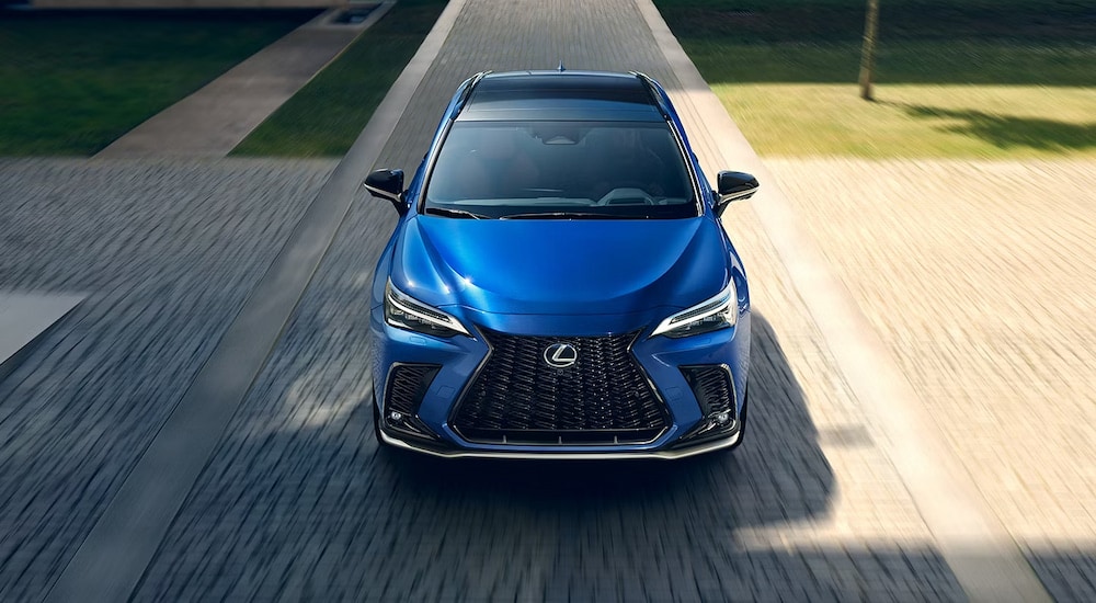 A blue 2024 Lexus NX 450h+ driving on a residential street.