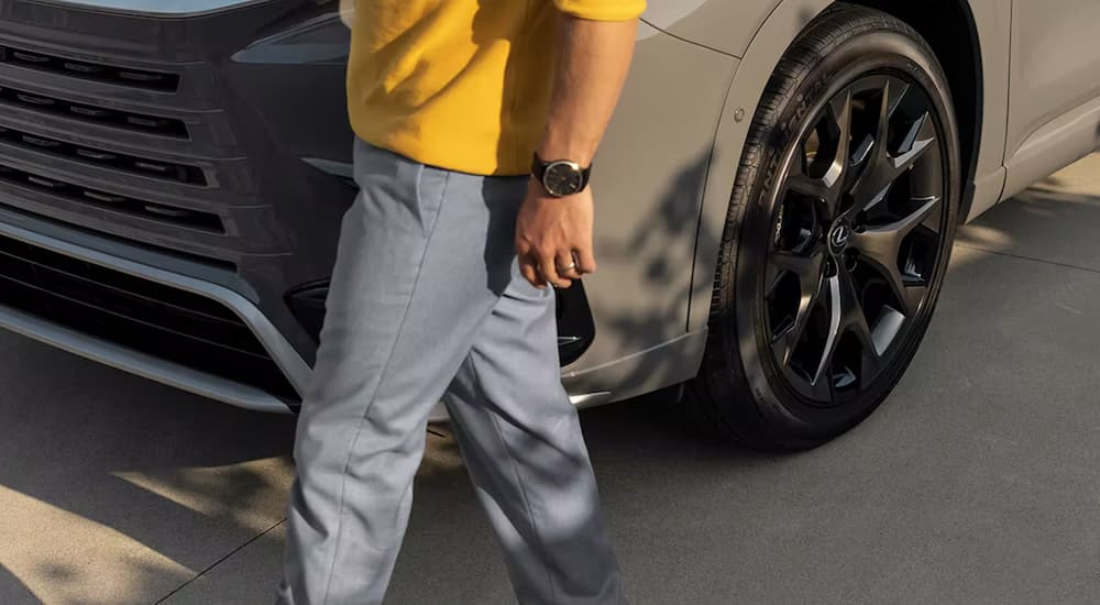 A close up of a person walking in front of a grey 2024 Lexus TX is shown.