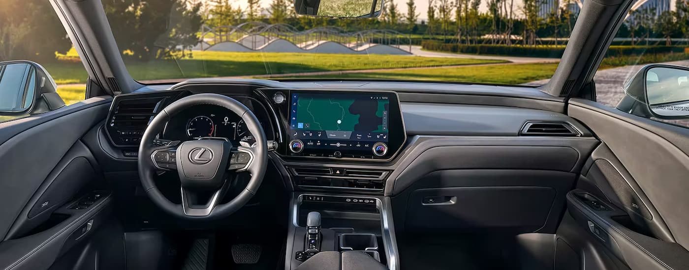 The black interior of a 2024 Lexus TX shows the steering wheel and dashboard.