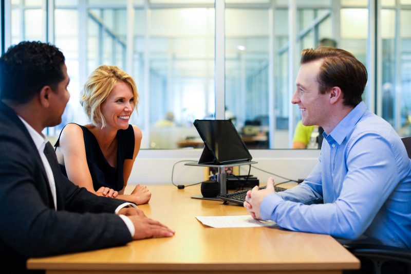  a salesman and a couple sitting at a desk