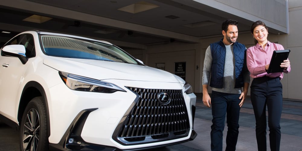 Lexus vehicle specialist shown helping a guest on a tablet.