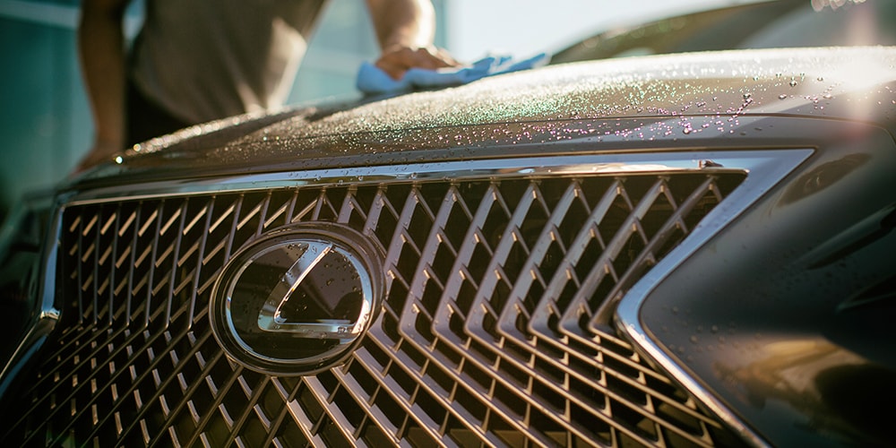 Man shown cleaning the hood of a Lexus vehicle.